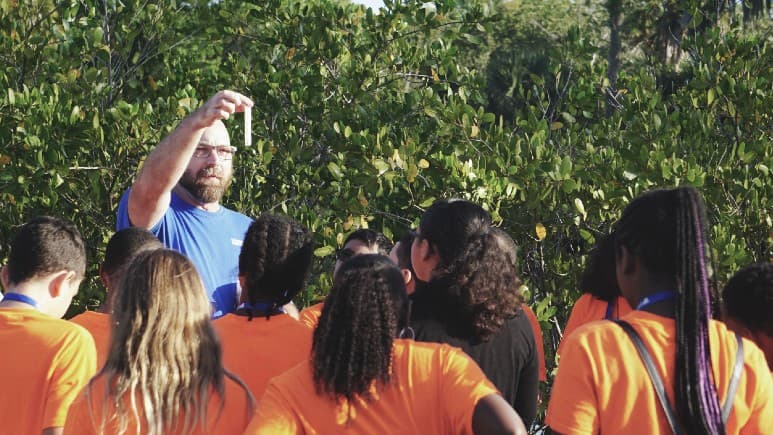 photo of science teacher teaching high school students outdoors