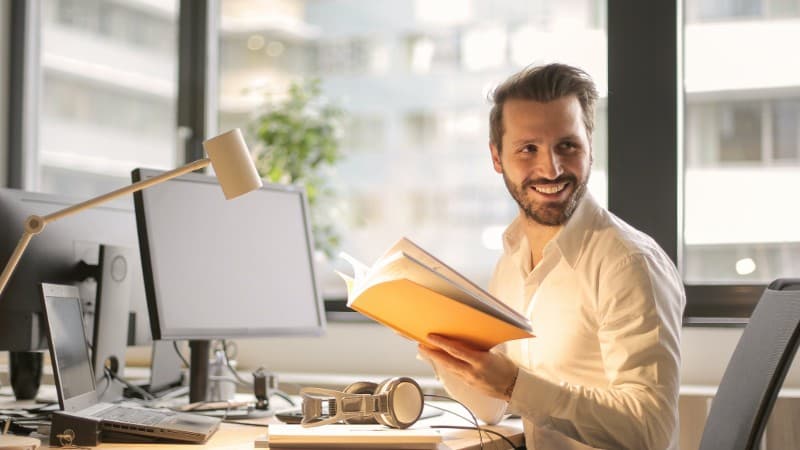 Office worker studying a policy manual and working at his desk